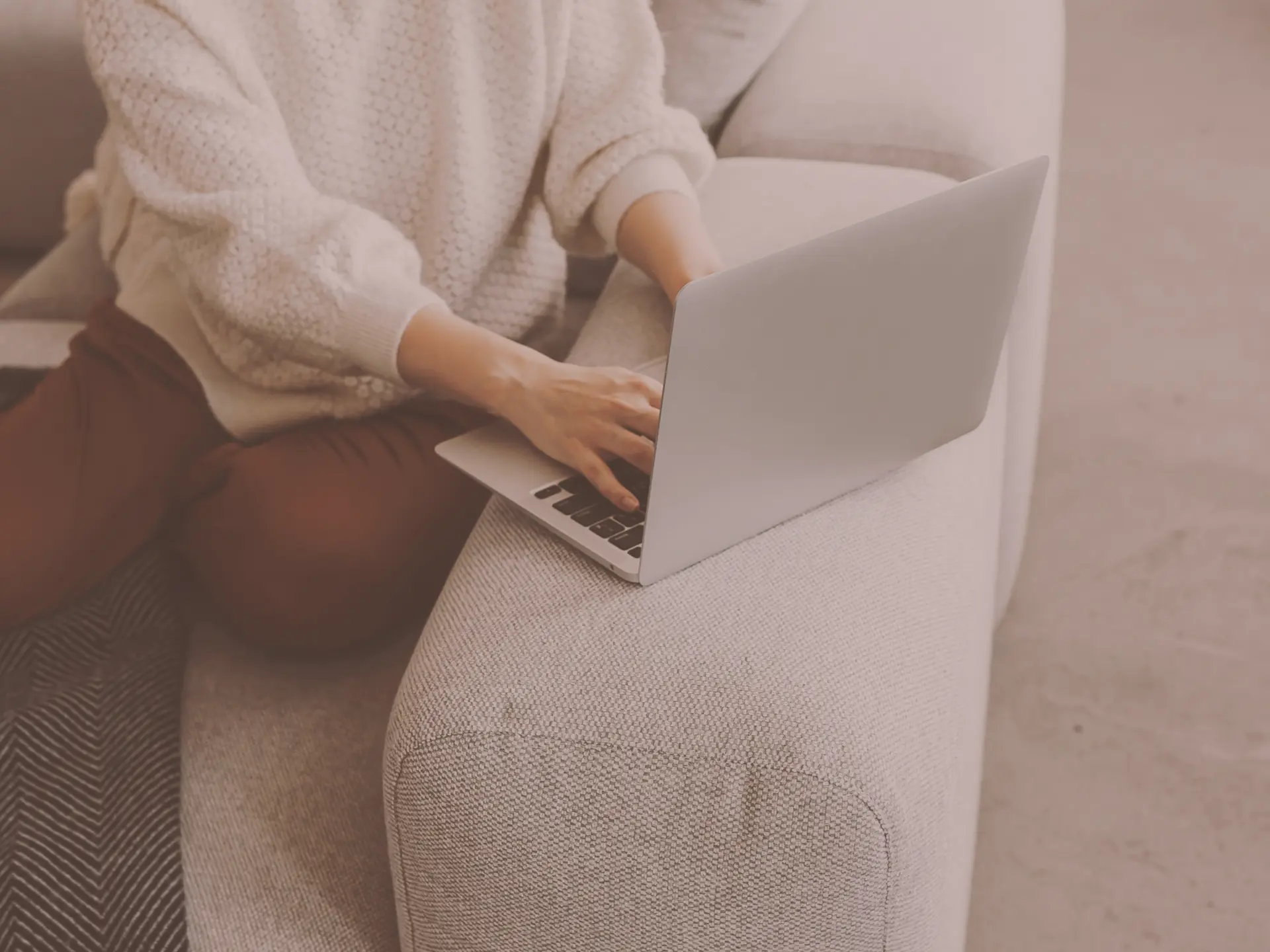 A coach working from a laptop on a couch